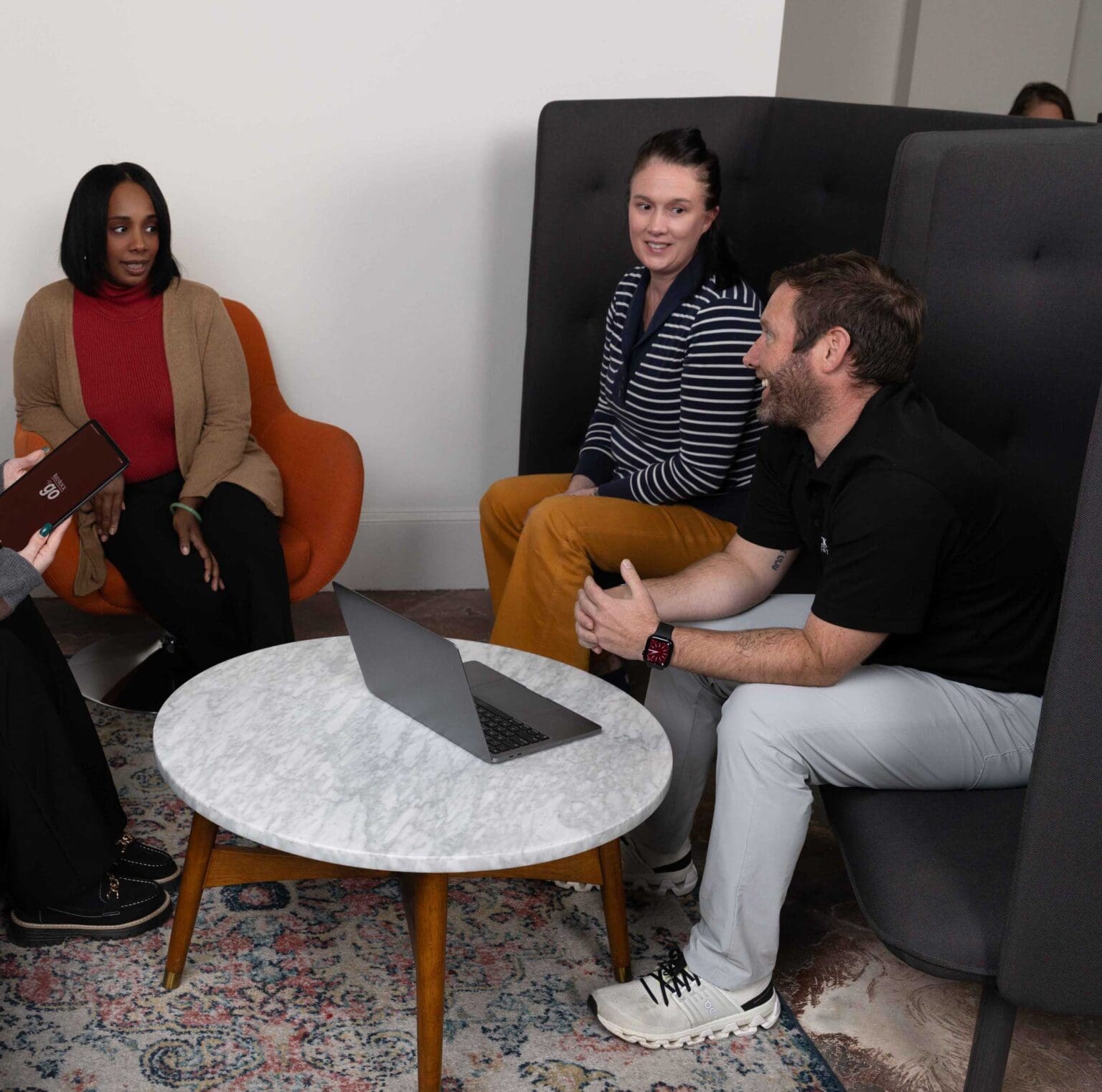 Team meeting around laptop in modern office lounge